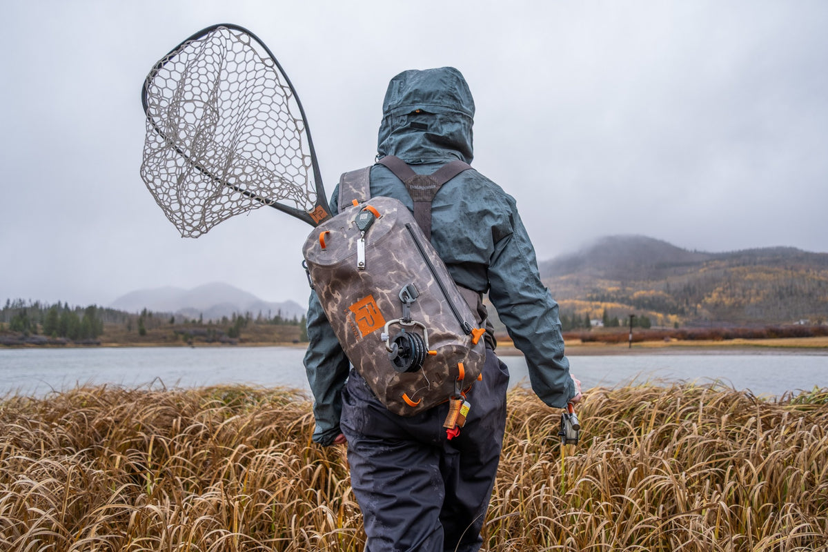 Fishpond Thunderhead HD Sling, Shadowcast Camo, worn by angler with net
