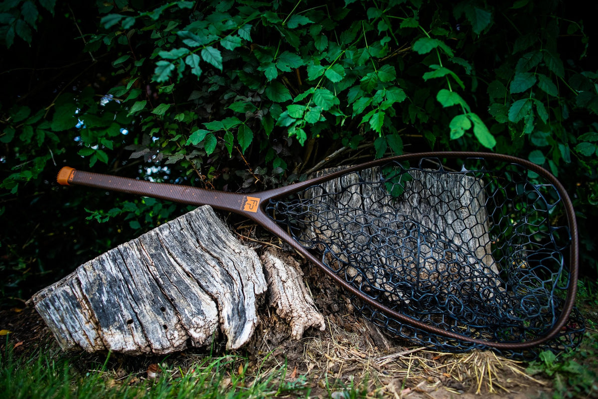 Fishpond Nomad El Jefe Net - 2.0, River Armor, resting on a tree stump