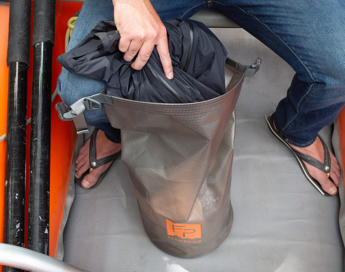 Fishpond Thunderhead Roll-Top Dry Bag - Smoke Grey, being packed with a jacket