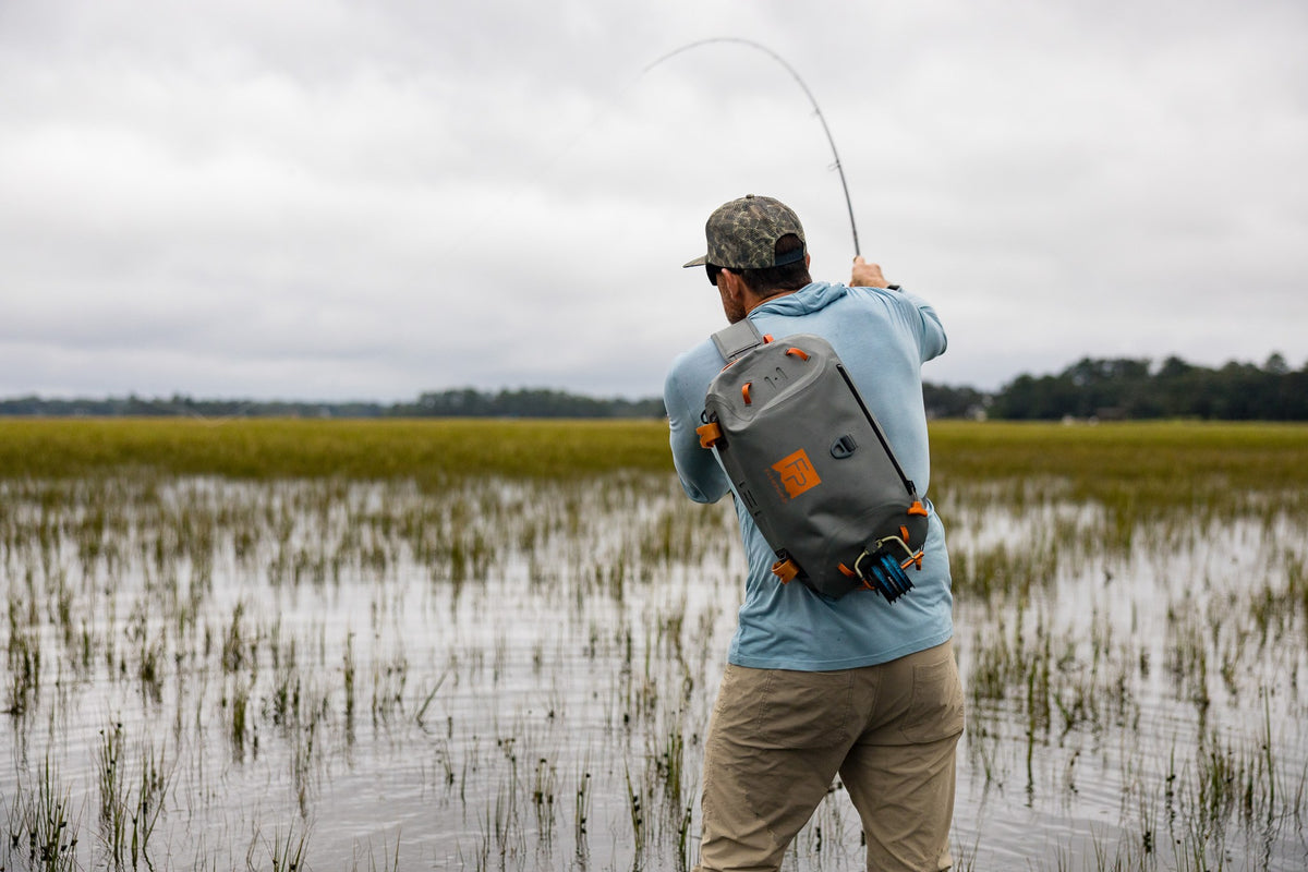 Fishpond Thunderhead HD Sling, Overcast Grey, worn by angler casting in a marsh