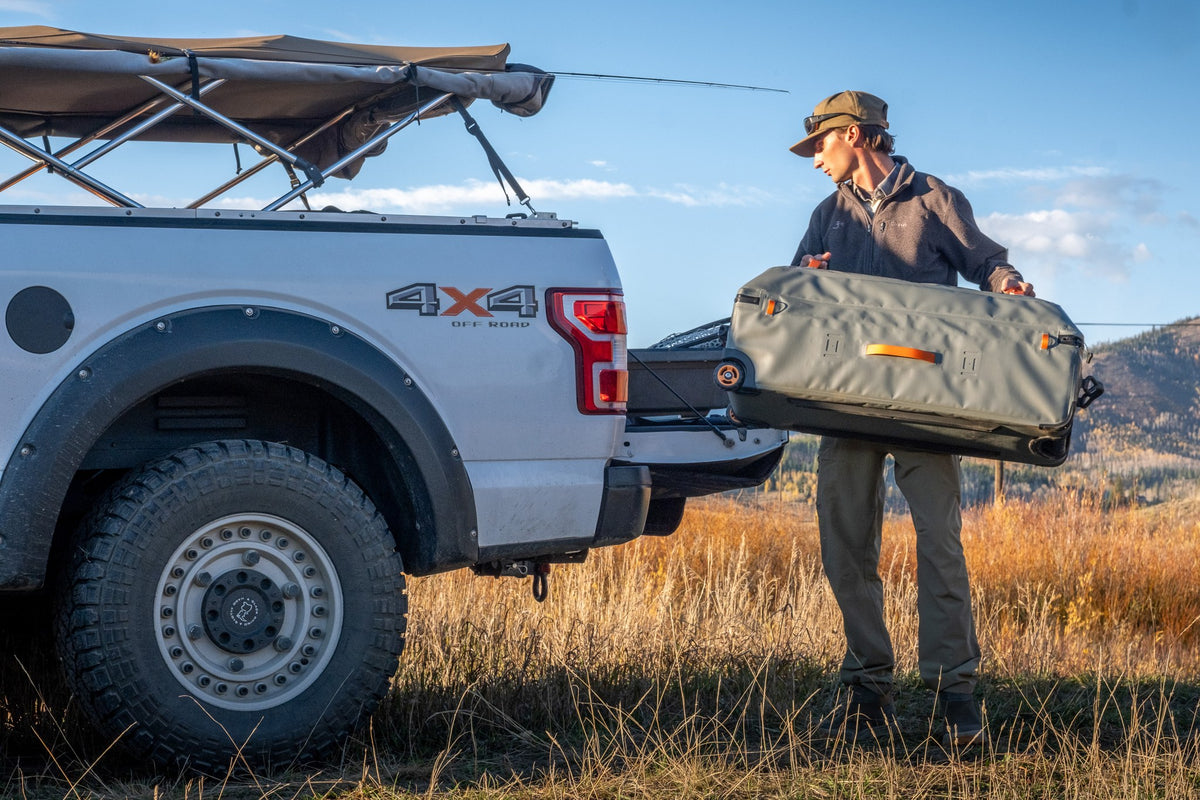Fishpond Backroad Large Rolling Duffel - Overcast Grey, being loaded into a truck bed
