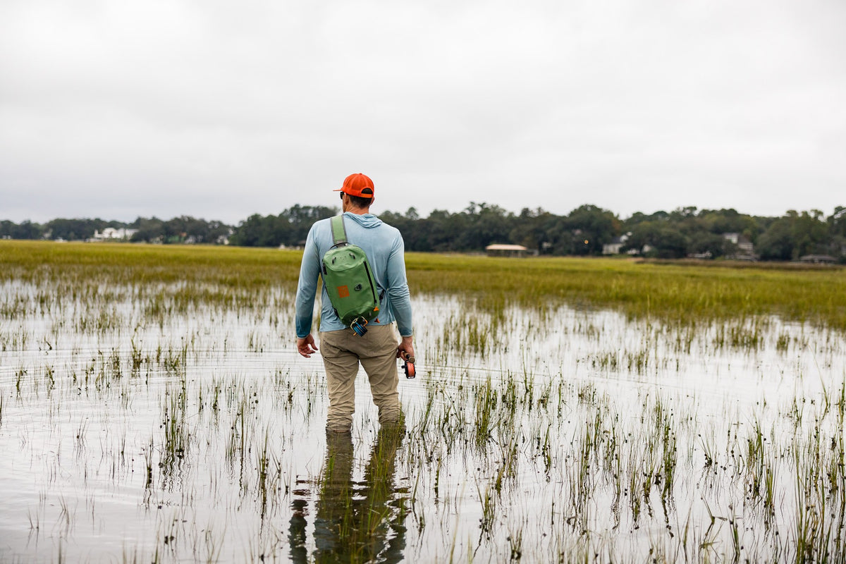 Fishpond Thunderhead HD Sling, Yucca, worn by angler wading in a marsh