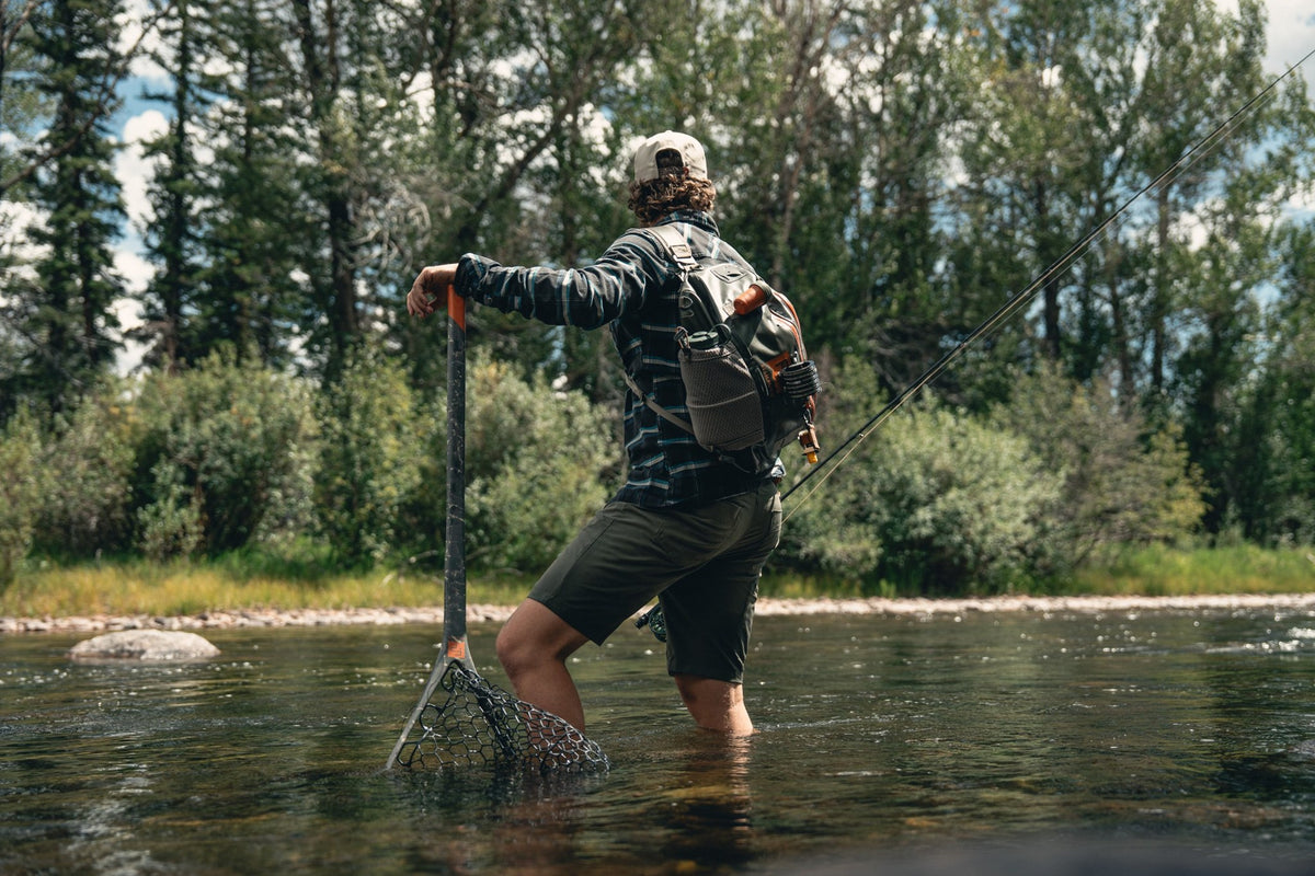 Fishpond Nomad El Jefe Grande - 2.0, Shadowcast Camo, angler wading with net