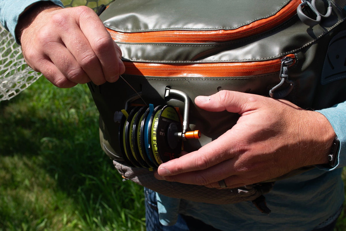 Fishpond Headgate Tippet Holder - PT Green, being mounted on a pack