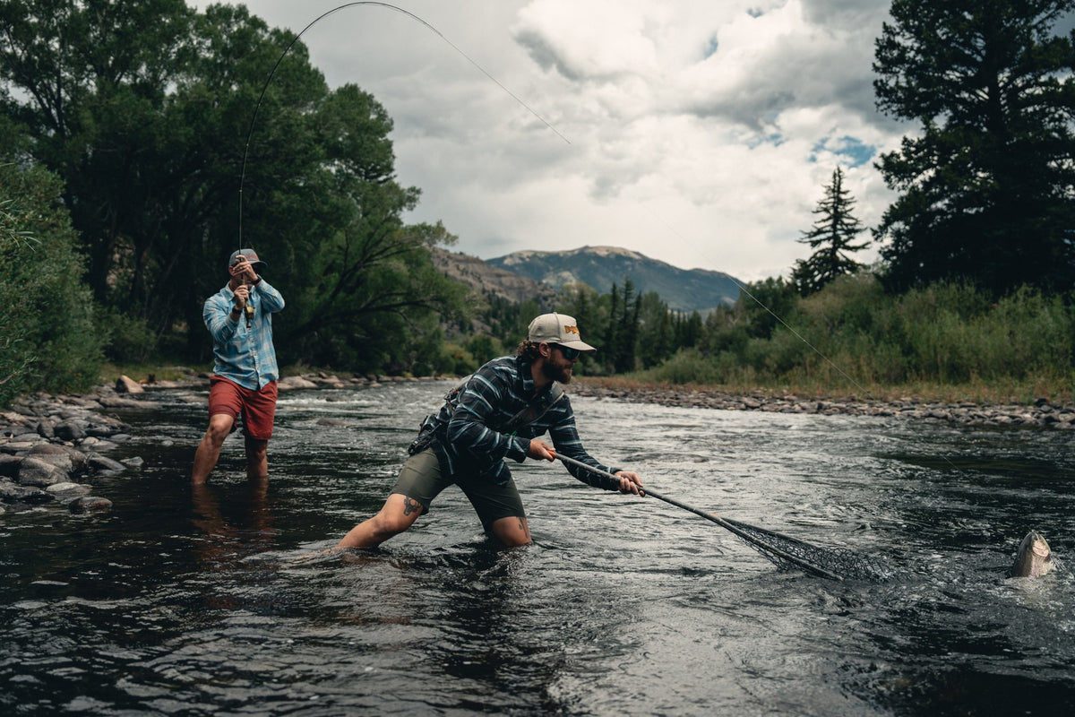 Fishpond Nomad Boat Net - Shadowcast Camo - 2.0, anglers netting a fish in a river