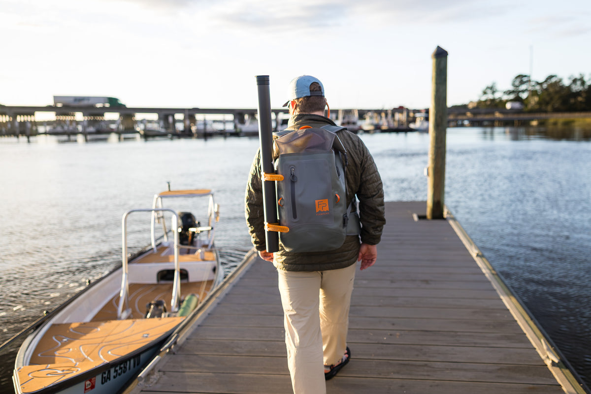 Fishpond Wind River HD Roll-Top Backpack, Overcast Grey, worn by angler on a dock
